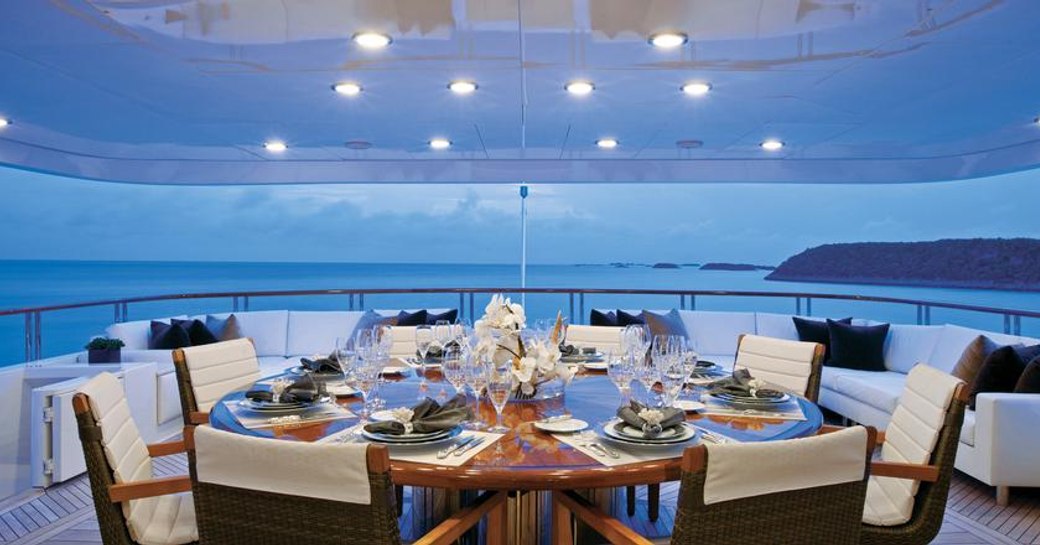 alfresco dining table on luxury charter yacht alessandra at sunset, with views of the ocean in the bahamas in background