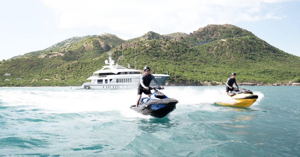 Charter guests on Jet Skis with charter yacht RELIANCE in the background