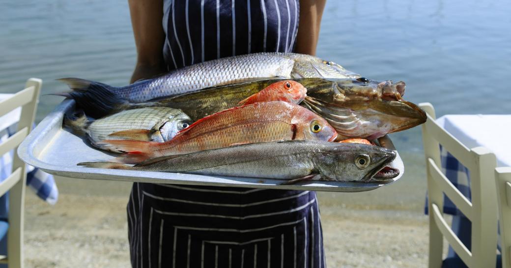 Waitress displaying locally caught fish for lunch