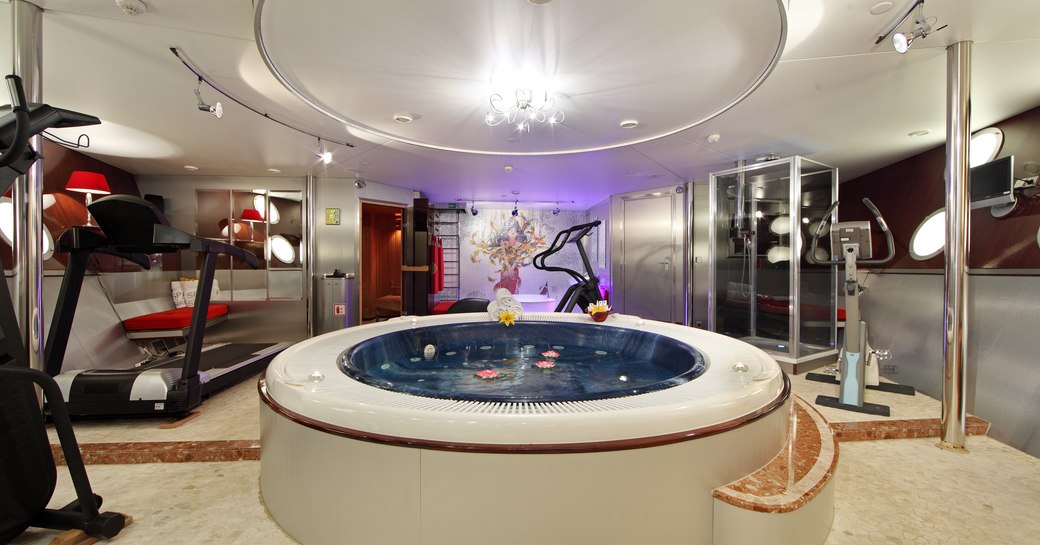 A large circular Jacuzzi emits a purple light inside superyacht SHERAKHAN