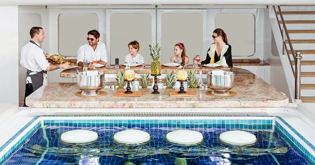 family is served meal overlooking pool on luxury yacht titania 