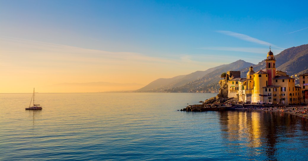 Mediterranean Sea at sunrise, small old town and yacht 