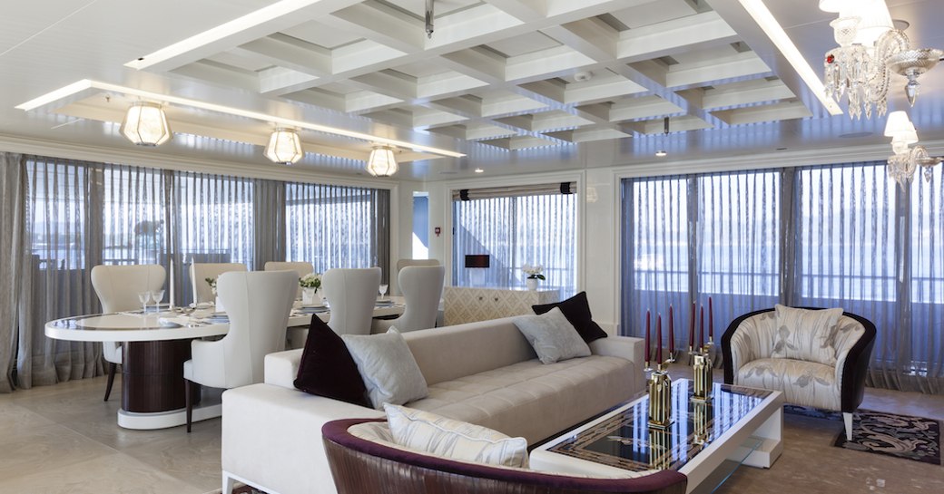 velvet sofas and custom-made dining table in the light and airy main salon aboard motor yacht Quinta Essentia