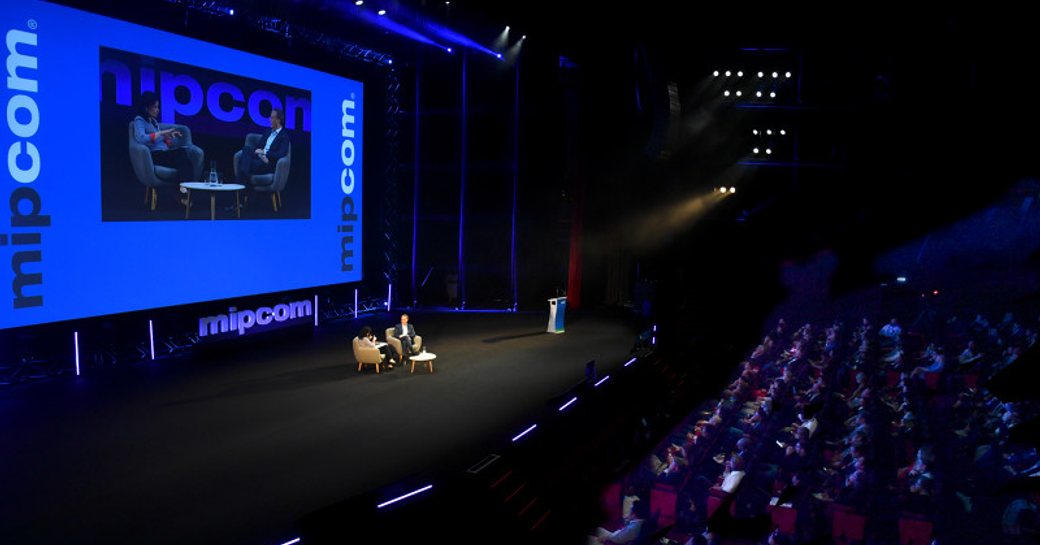 MIPCOM auditorium with a keynote speaker presenting on stage.