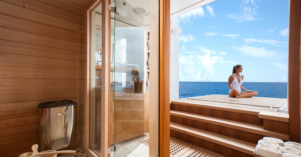 A charter guest sits cross-legged on a foldout balcony attached to a superyacht