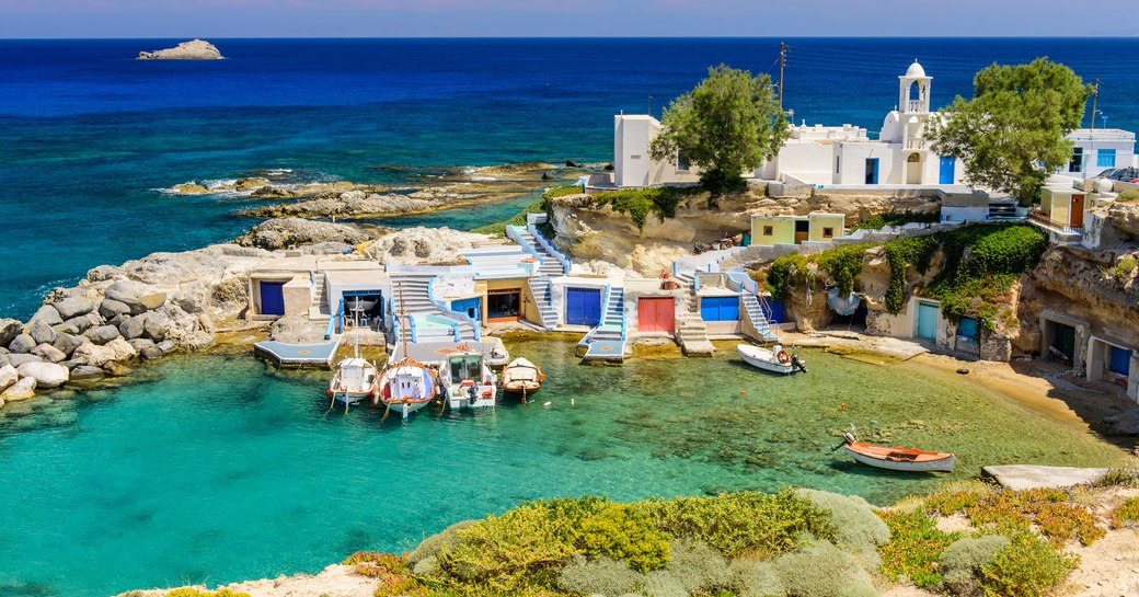 milos, an island in greece, with pretty village and little white chapel in small bay