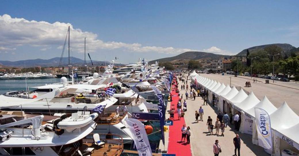 Visitors to Mediterranean Yacht Show talking to crew on red carpet, surrounded by berthed motor yachts.