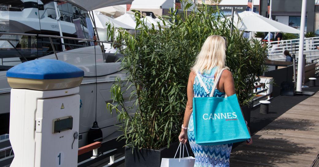 Lady walking along the docks of the Cannes Yachting Festival with shopping bags