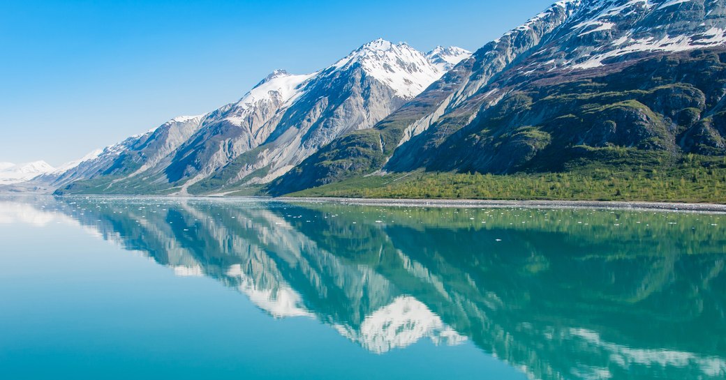 mountains along the coast of alaska, overlooking bright blue ocean and covered by snow