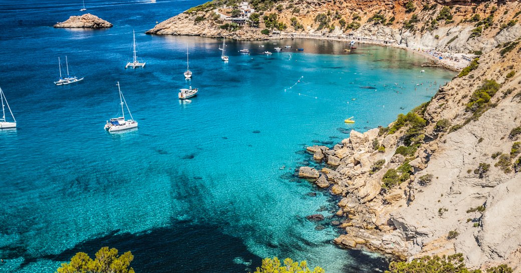 little blue bay in ibiza, with yachts on the water