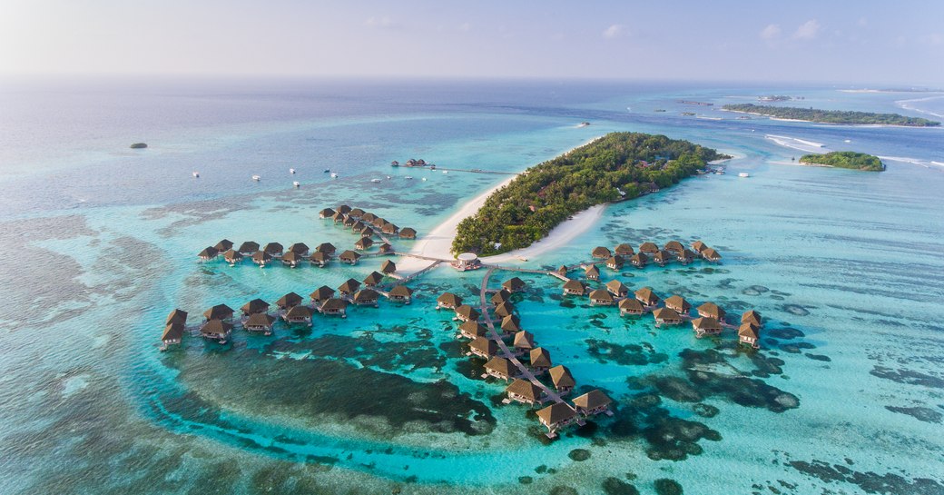 bungalows perched over the water and azure waters in the Maldives