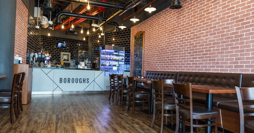 Interior image of Boroughs cafe and restaurant in Abu Dhabi, with sofa seating and chairs with bar in background and exposes ceiling