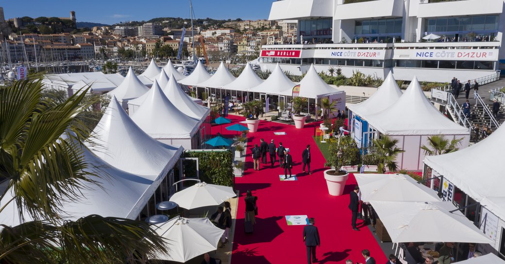 Display of exhibition tents along red carpet at Cannes MIPIM, visitors walking along the carpet.