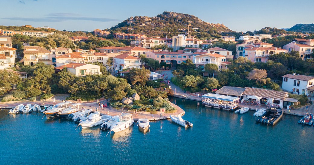 Port of Porto Rotondo in Sardinia, with houses by the water and charter yachts in the bay