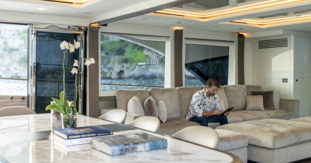 Main salon on superyacht VIVALDI, with man sitting reading on sofa