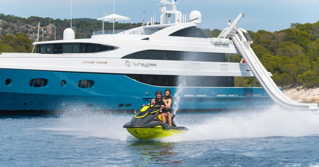 Charter guests on a Jet Ski with charter yacht HOLDIN' MY OWN in the background