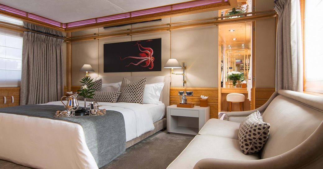 Master cabin onboard charter yacht BELLA STELLA with a central berth and a cream sofa in the foreground