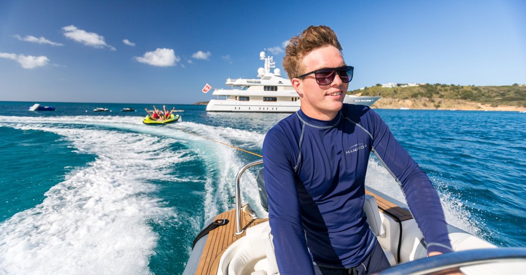 crew member in a tender pulls along inflatable toy with superyacht HANIKON in the background