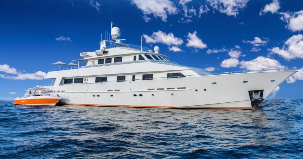 Luxury yacht LIONSHARE at anchor with orange tender alongside