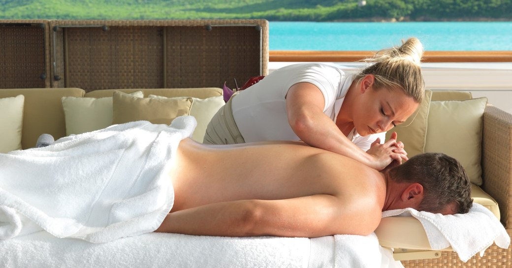 a guest on a luxury yacht charter on board superyacht the wellington enjoying the massage on the aft deck of their cruise in mallorca