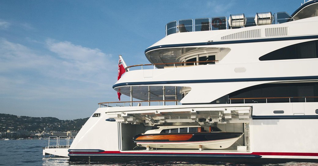 A superyacht with its tender door open and storing a classical looking tender