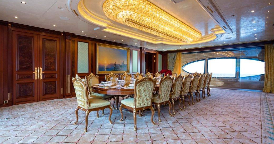 Interior dining room with long table and ornate seating onboard charter yacht BLACK PEARL