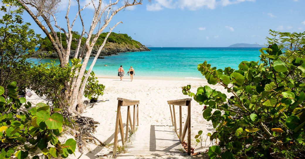 couple walking towards clear blue waters on Trunk Bay in the Virgin islands