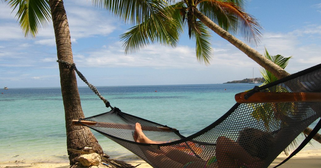 Woman relaxing in a hammock on a beach in Fiji