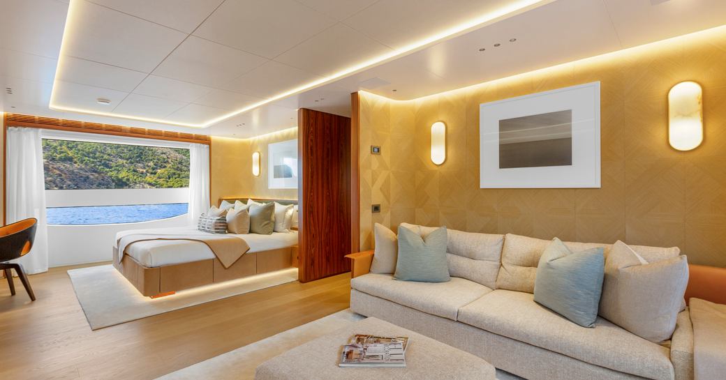 Overview of master cabin onboard charter yacht LIV LOVE with seating area forward and large bed in background