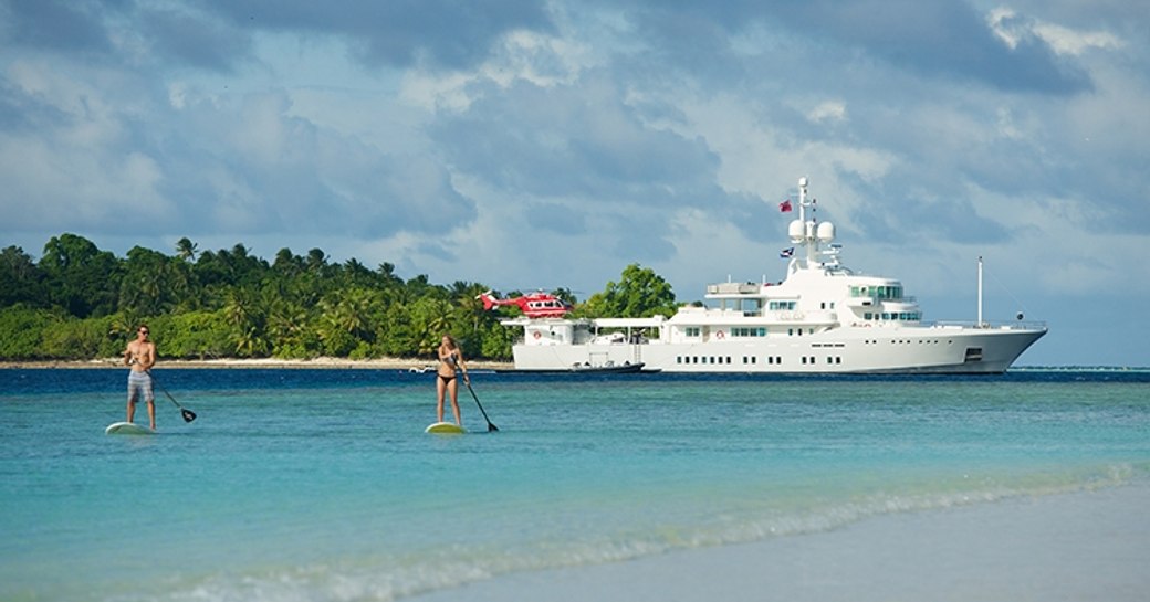 Superyacht SENSES anchors at charter guests play on stand-up paddle boards