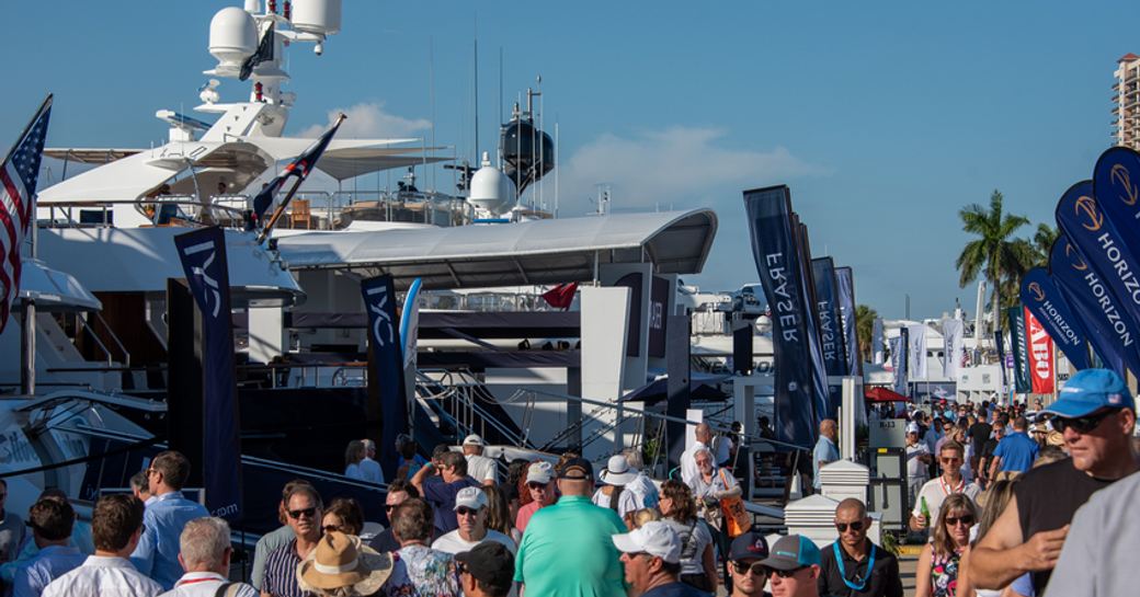 Glimpse of some exhibitors at FLIBS, yachts moored on either side of floating dock with hundreds of visitors walking in between.