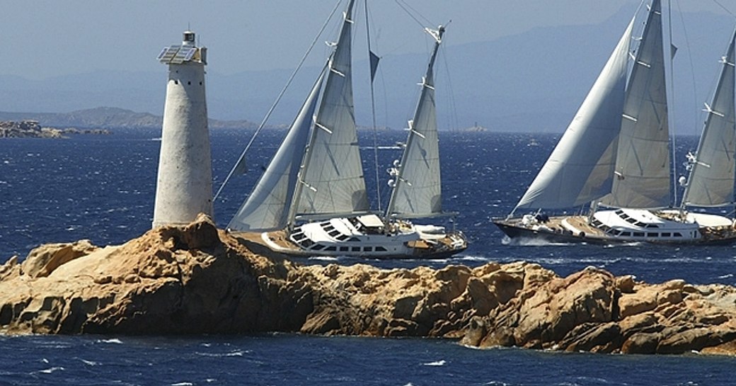 Perini Navi Cup competitors underway by lighthouse, surrounded by sea