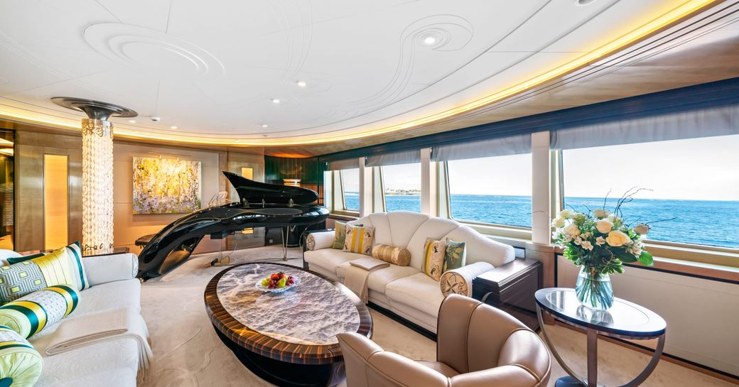 Interior seating area with piano and large windows onboard charter yacht AMARYLLIS