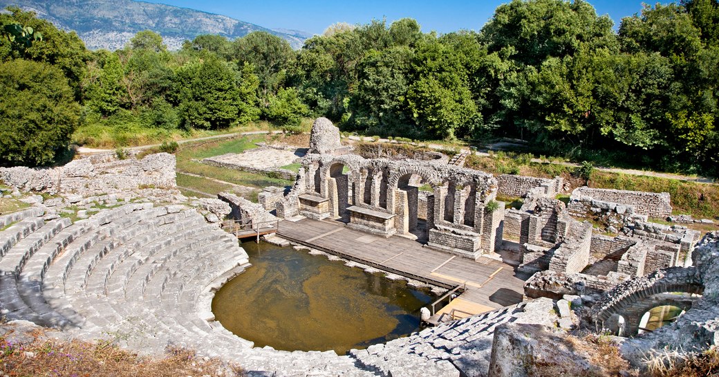 ancient Greek theatre ruins seen from above with trees beyond