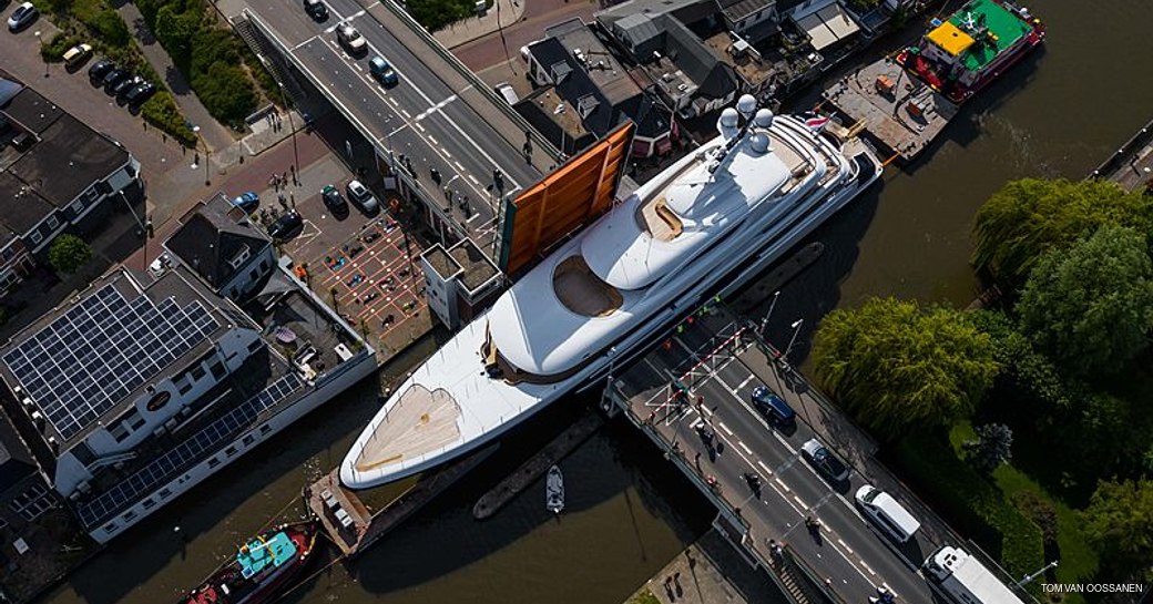 aerial image of luxury yacht podium squeezing through gap in canal