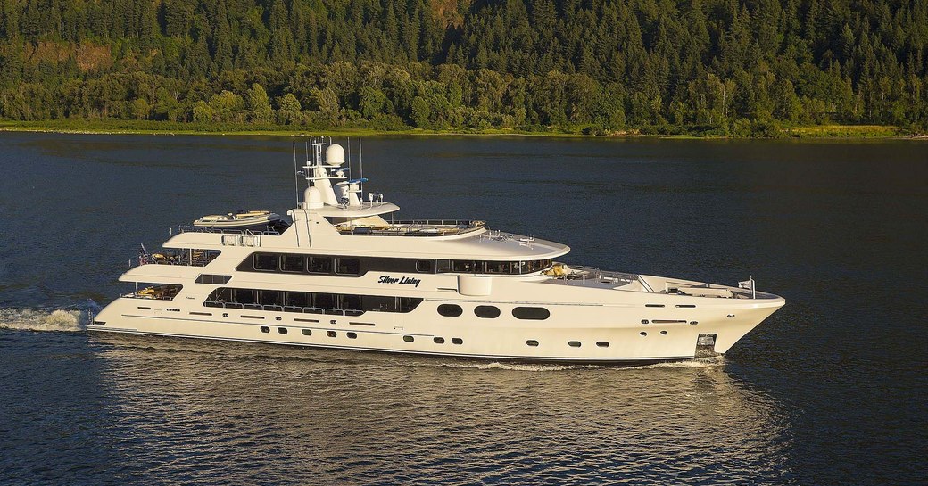 Superyacht Silver Lining cruising against a green coast