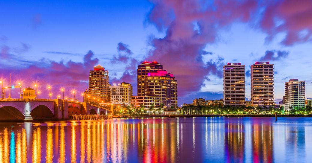 Palm Beach skyline at dusk, Flagler Drive lit by abundance of street lights, all of which reflecting on still waters.