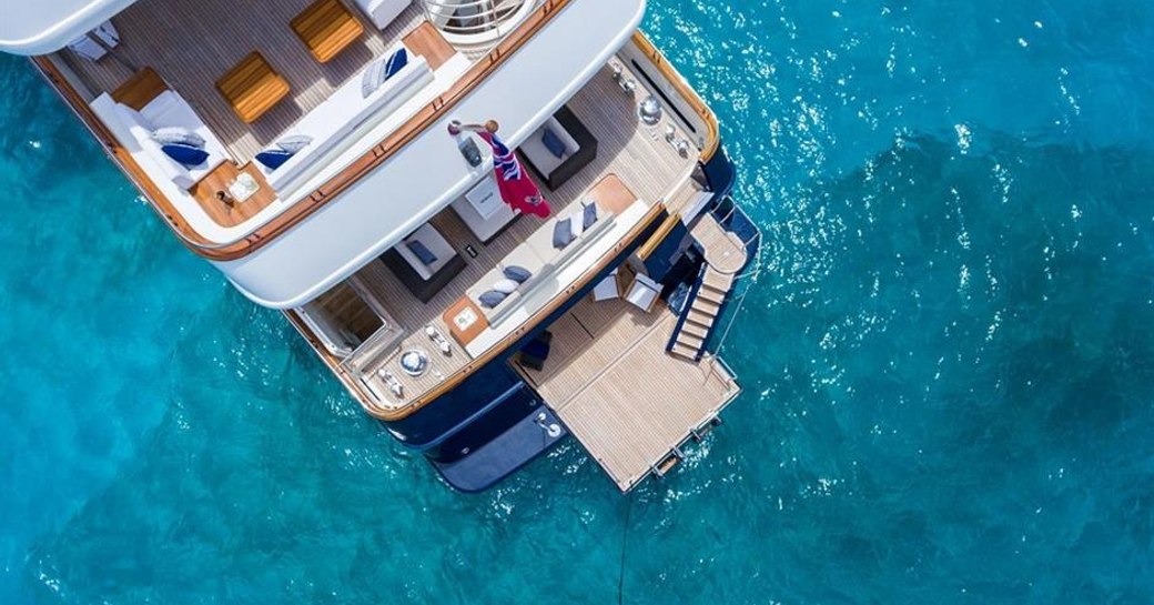 an aerial shot f luxury yacht fabulous character's swim platform and upper three decks as she anchors in the caribbean