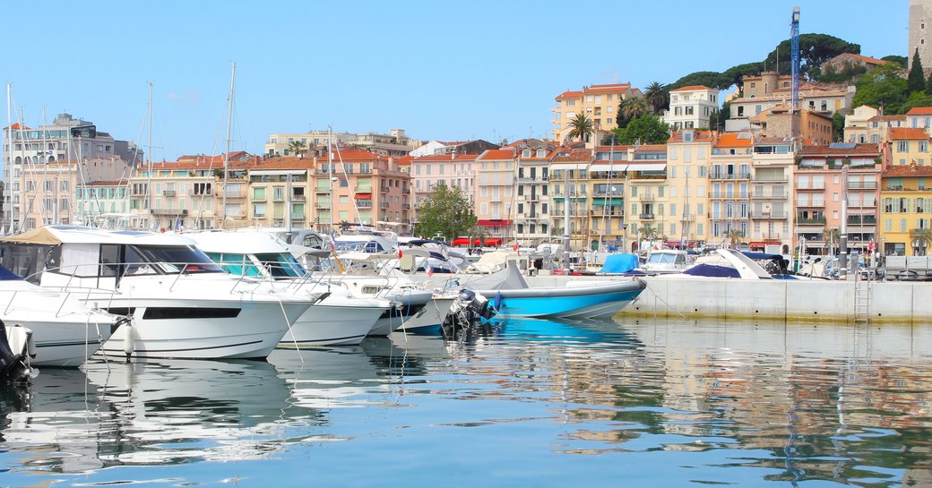 Sea level view of Cannes Vieux Port. Motorboats berthed on port side with Cannes settlement visible in background.