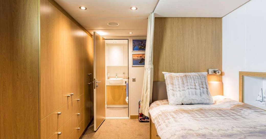 Bright interior of Game Changer yacht, showing bed and wooden furniture and door open to bathroom