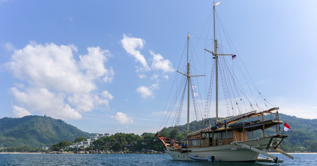 Charter yacht LAMIMA at-anchor outside the Kata Rocks resort 