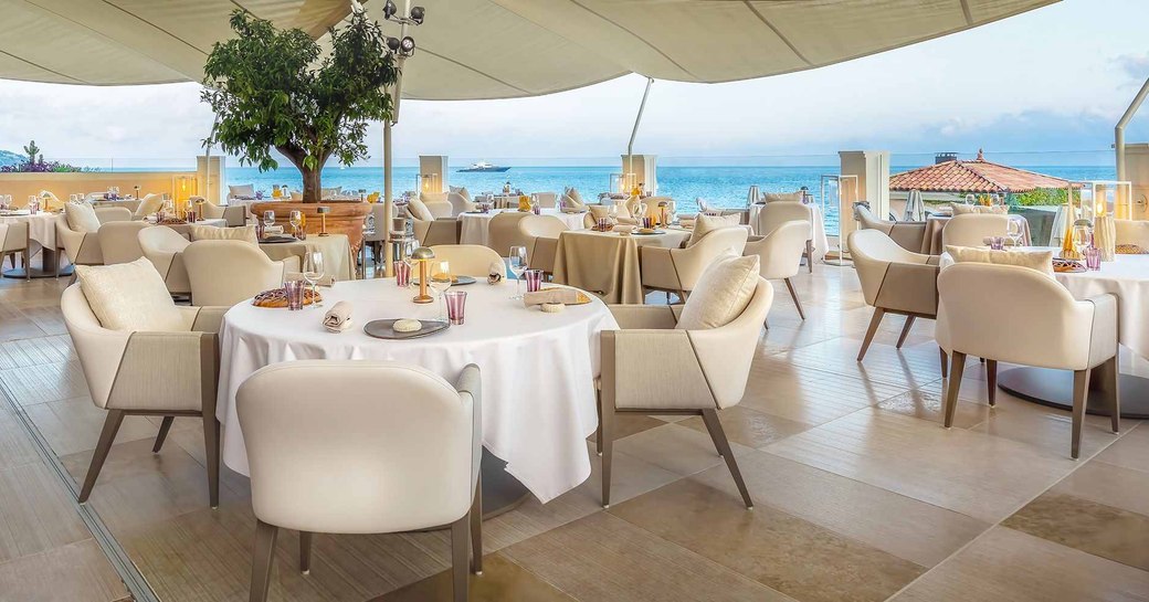 terrace of blue bay restaurant in monaco, with balcony overlooking the ocean and white shading above the tables