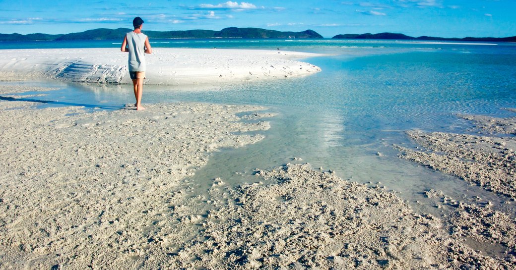 charter guests strolls along a beautiful white sand beach on the Whitsundays