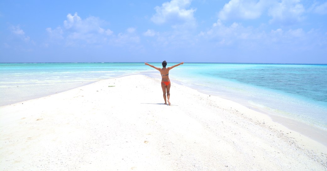 White sand bank in the Maldives with girl running on the sand