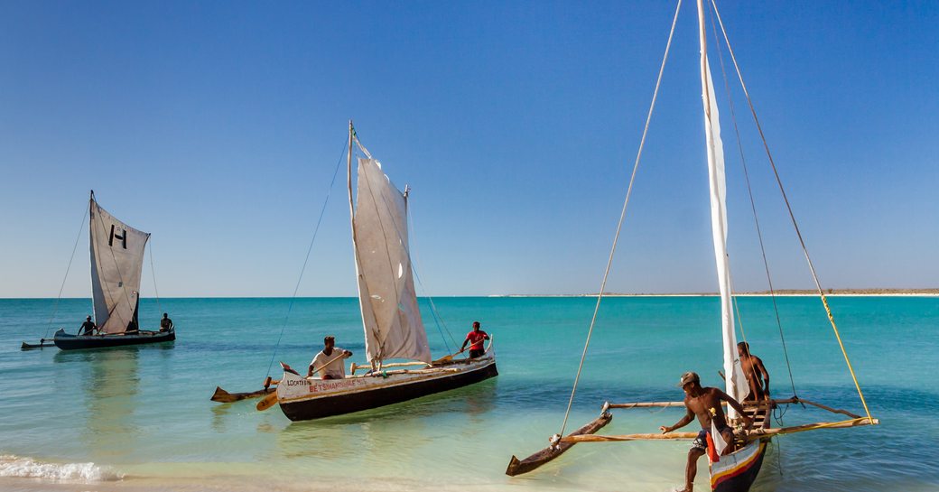 3 small sailing craft lined up together on the shore