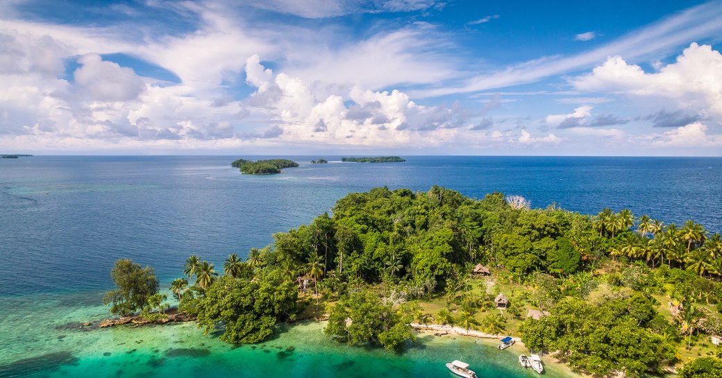 isand in papua new guinea covered in jungles with turquoise ocean surrounding