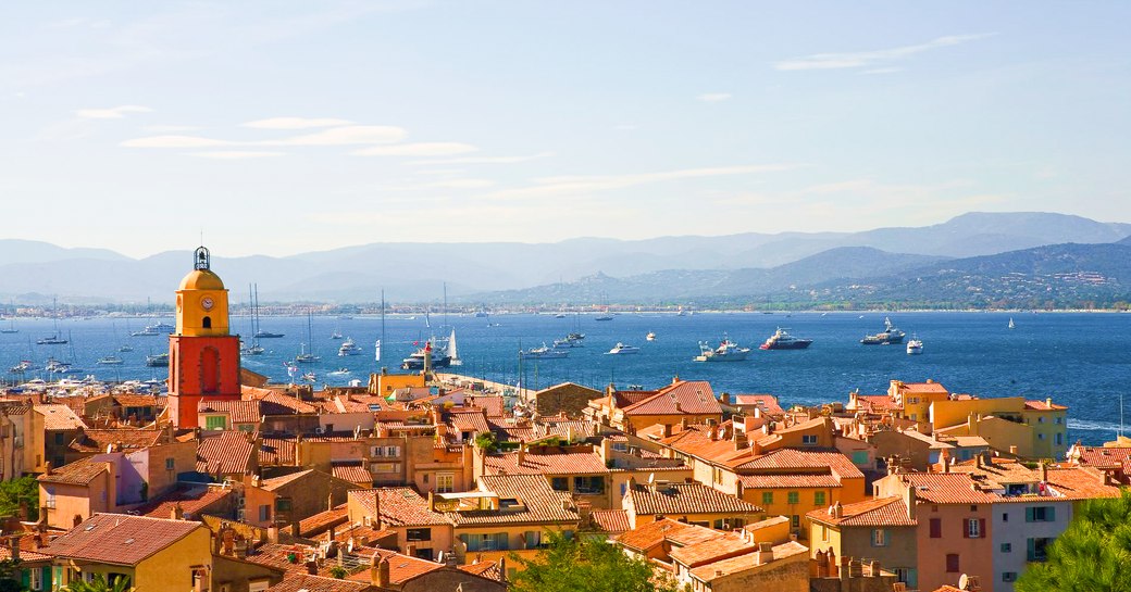 A collection of superyachts gathered outside of a small French town