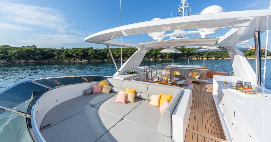 sunpads and dining table beyond on sundeck of luxury yacht DYNAR