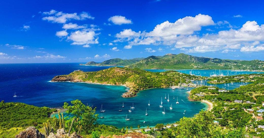 Sailing yachts and motor yachts cruising in the bright blue waters of Antigua