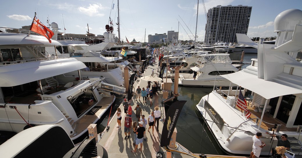 Motor yachts moored along pontoon at Palm Beach International Boat Show, visitors walking between yachts.